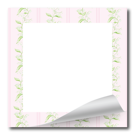 A square white card or notepad with a decorative border in soft pink and light green, featuring a curled bottom-right corner to show a glossy finish.