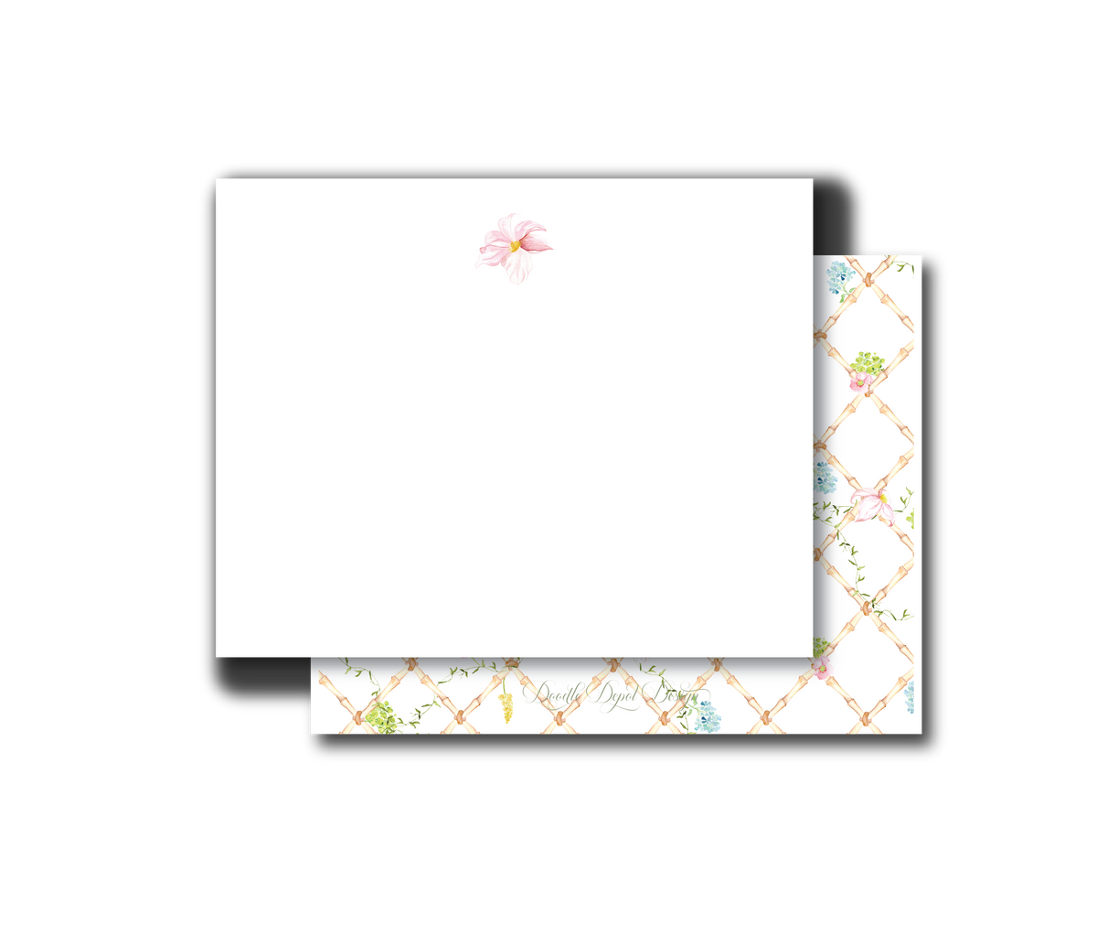 A white stationery card with a small pink floral illustration near the top, shown with a matching patterned envelope featuring a gold trellis design and pastel floral accents on a white background.