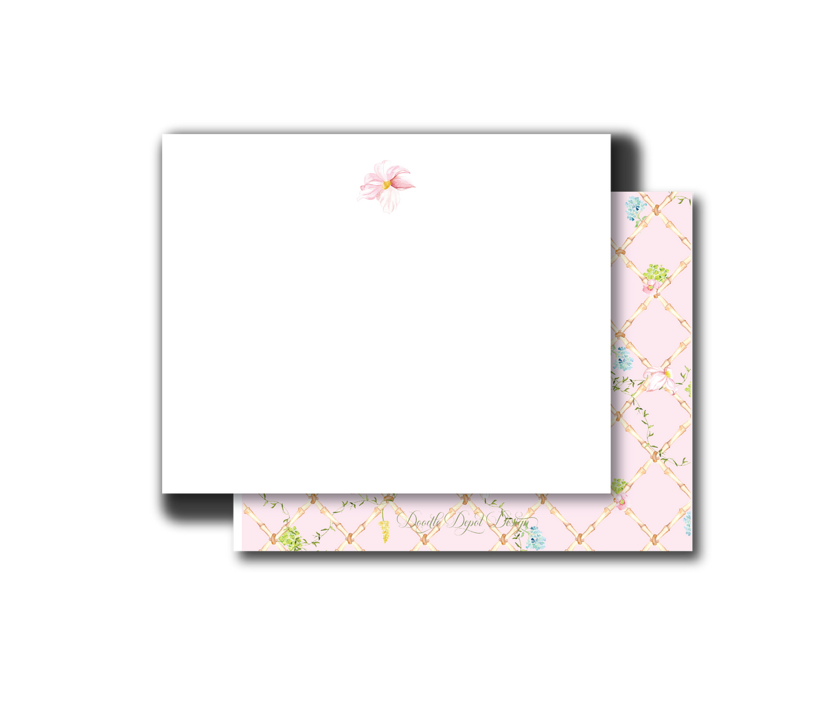 A white stationery card with a small pink floral illustration near the top, shown with a pink patterned envelope or backing featuring a gold lattice design and small green and blue floral accents, on a plain white background.